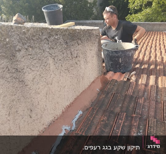 אדם עובד על גג רעפים עם דלי וחומר איטום